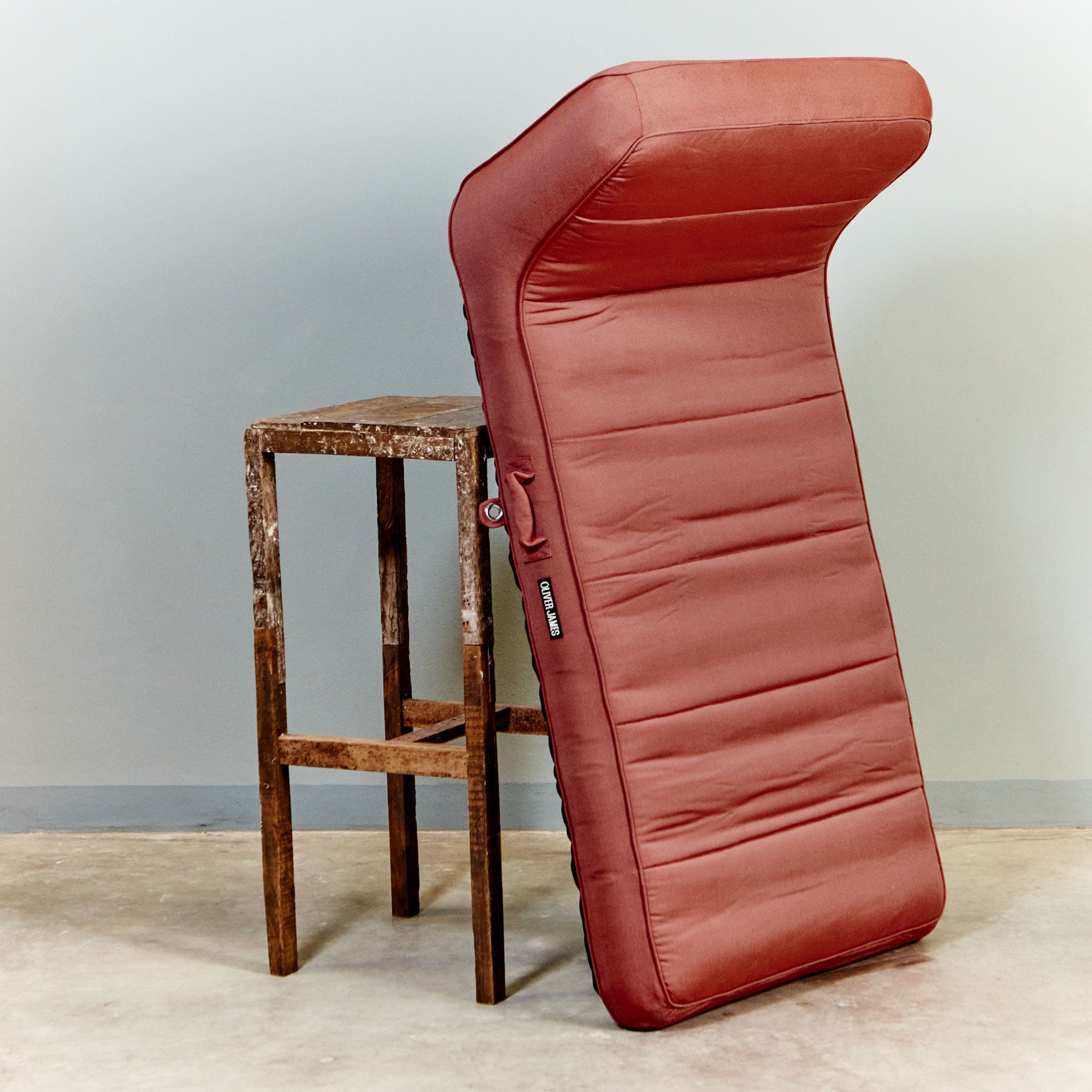 A red luxury pool float leaning against a stool in a warehouse.