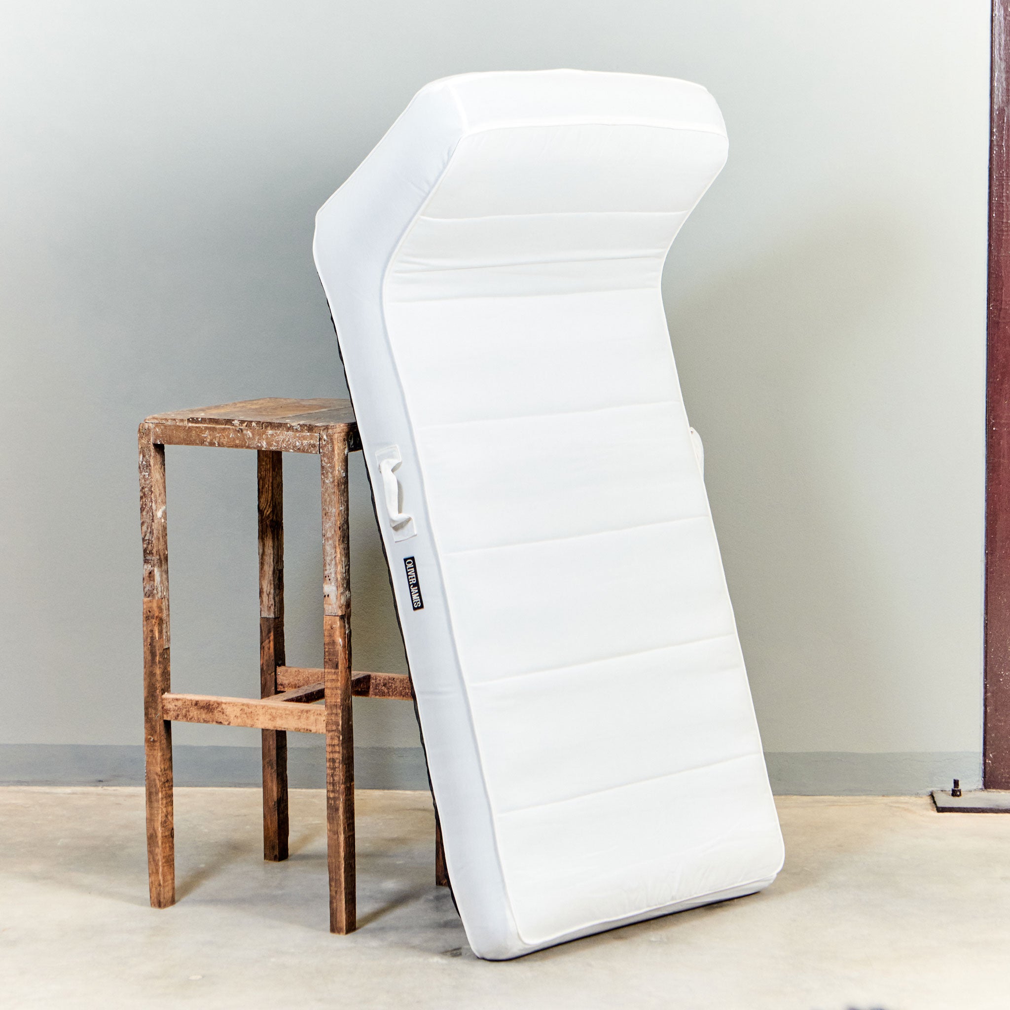 A white luxury pool float leaning against a stool in a warehouse.