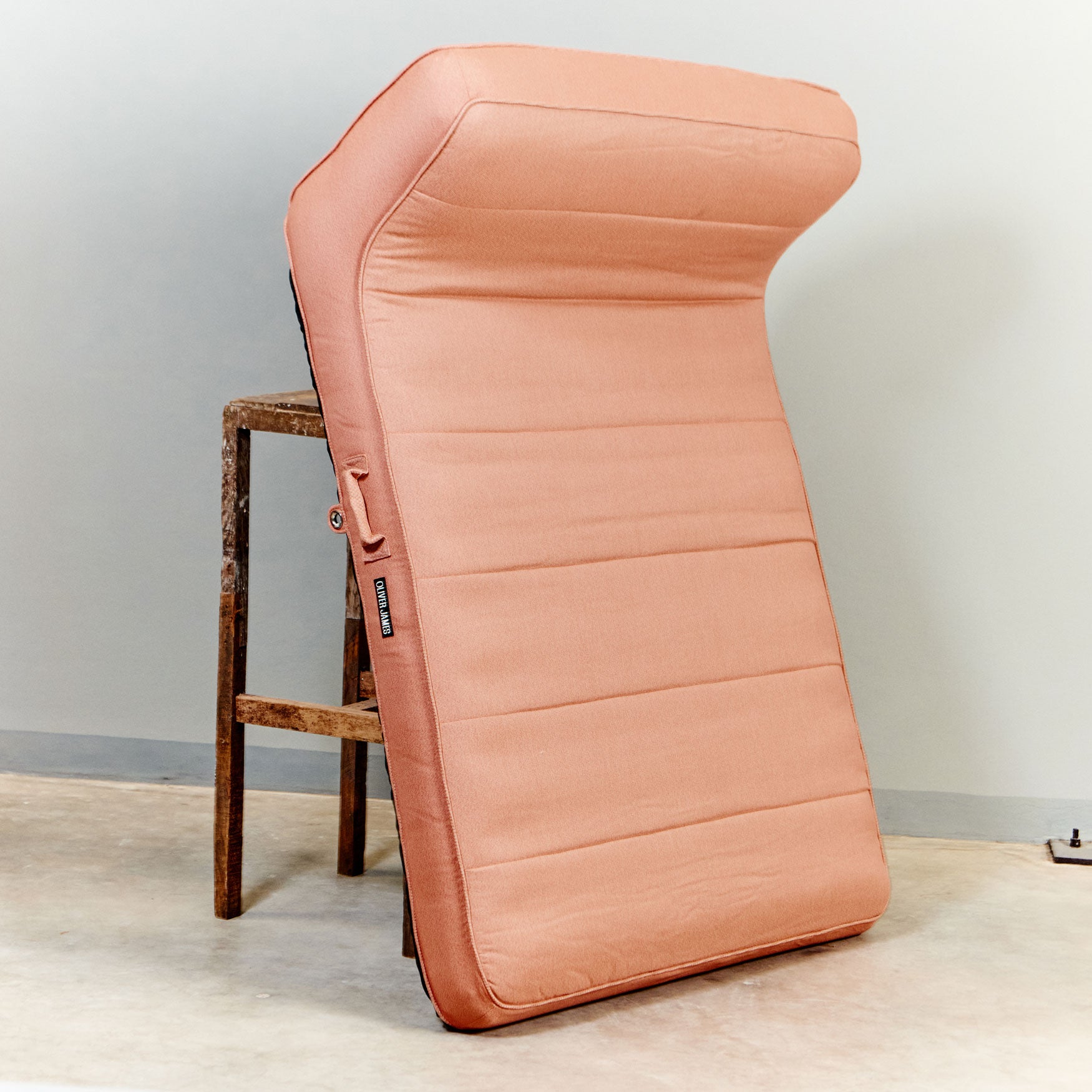 A orange luxury pool float leaning against a stool in a warehouse.