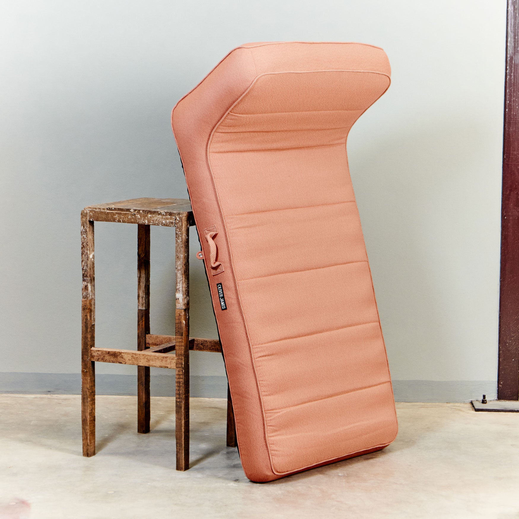 A orange luxury pool float leaning against a stool in a warehouse.