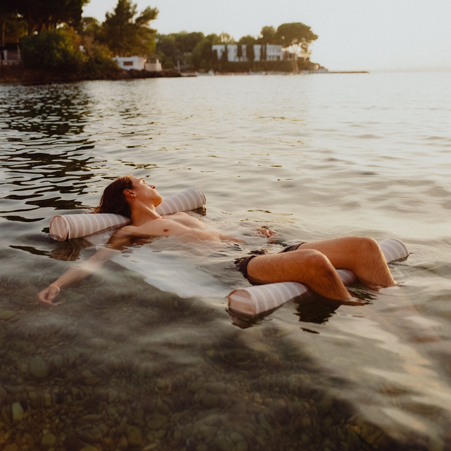 A man floating in the ocean on a beach float for adults.