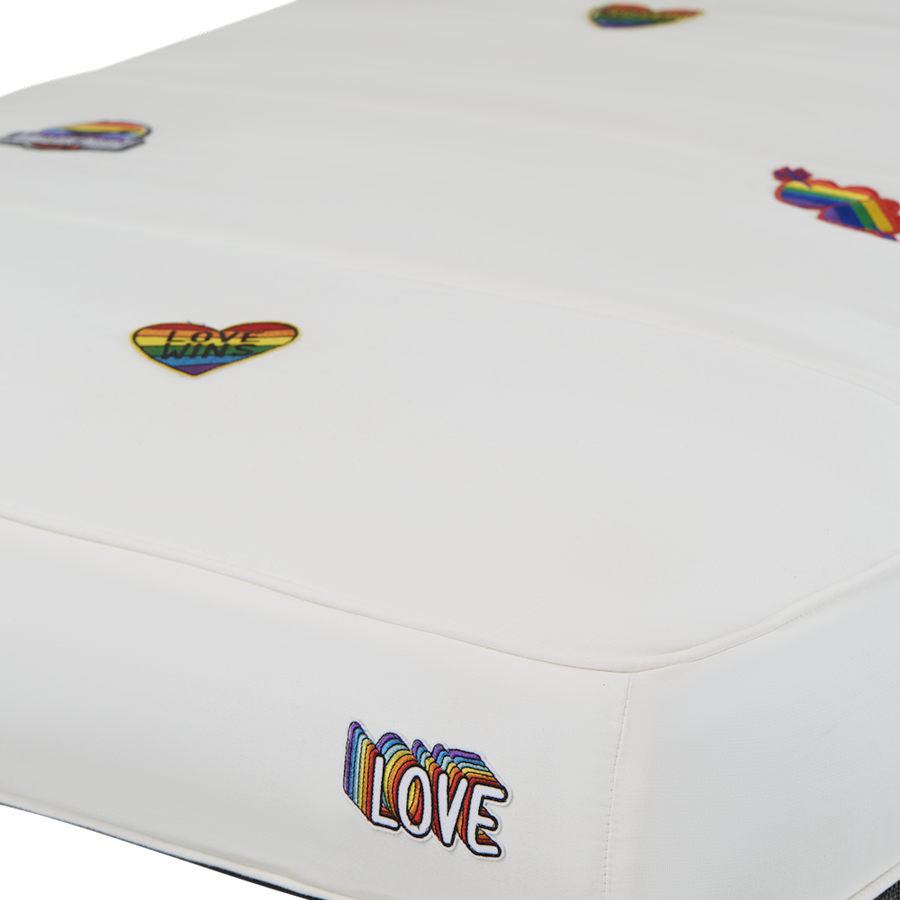 A white luxury pool float with LGBTQ fabric patches sewn onto the cover.