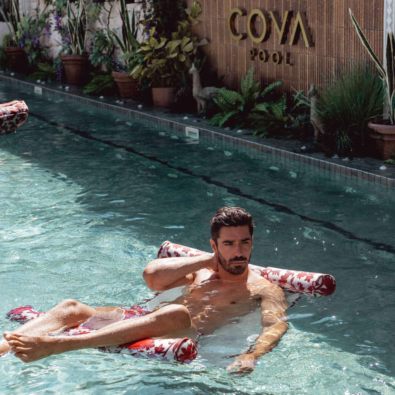 A man floating in a luxury pool float hammock at the Coya pool in Marbella.