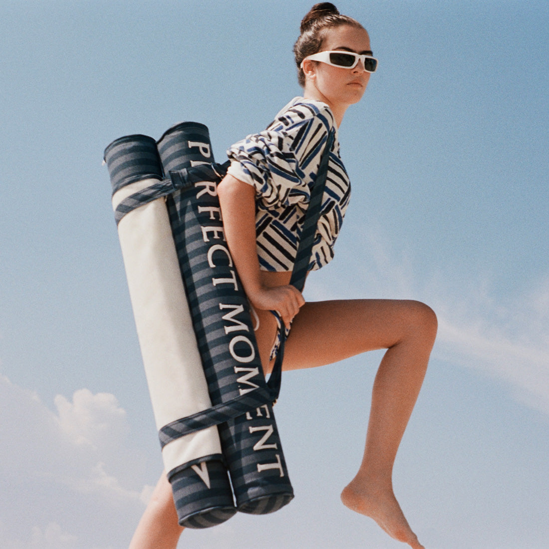 A women jumping across the sky with a luxury pool float on her back.