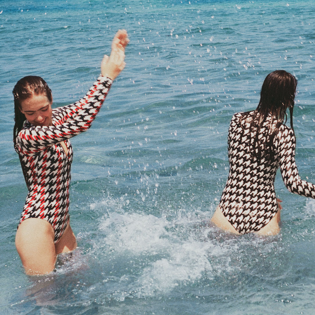 Two girls playing in the sea splashing eachother.