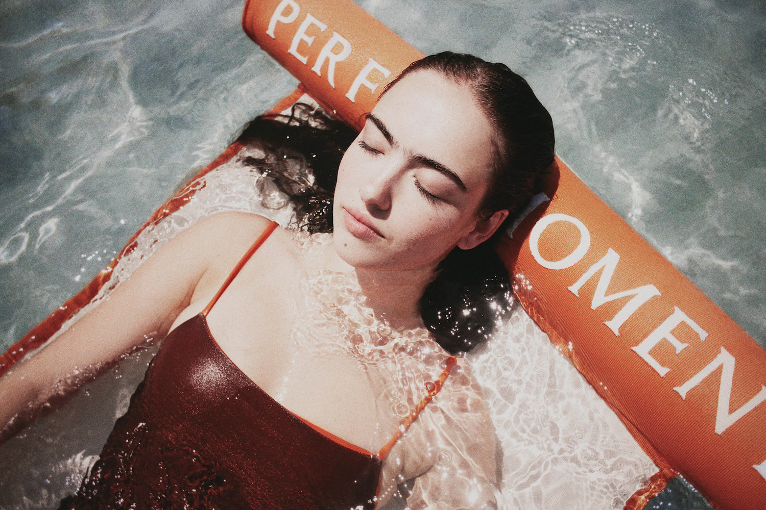 A women in water, close up of her face relaxing on a luxury pool float.