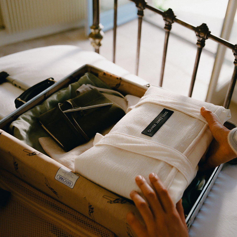 A white luxury pool hammock being unpacked from a suitcase on a bed
