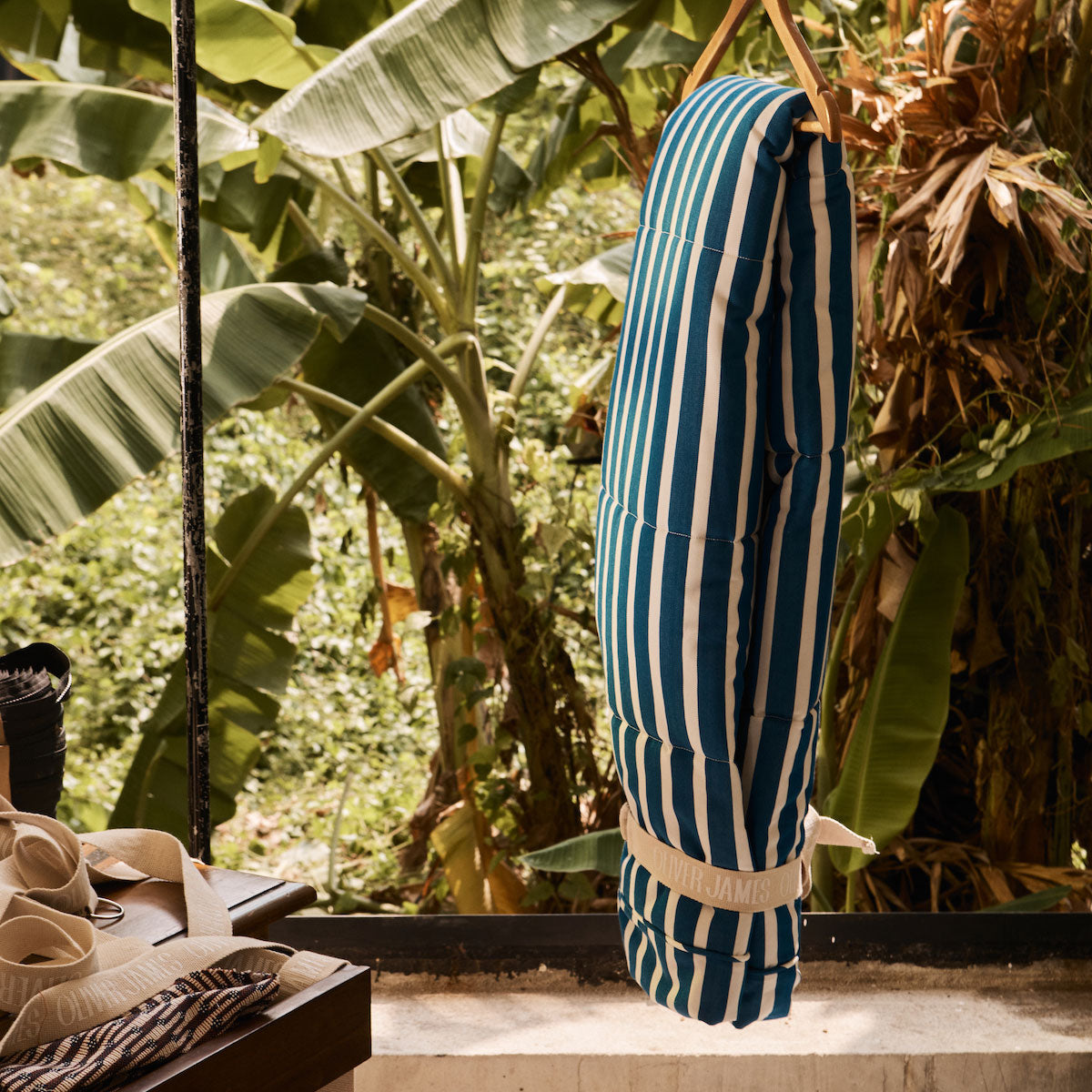 A luxury pool float cover hanging on a cloths rack with tropical plants in the background and luxury lilo components in the foreground.