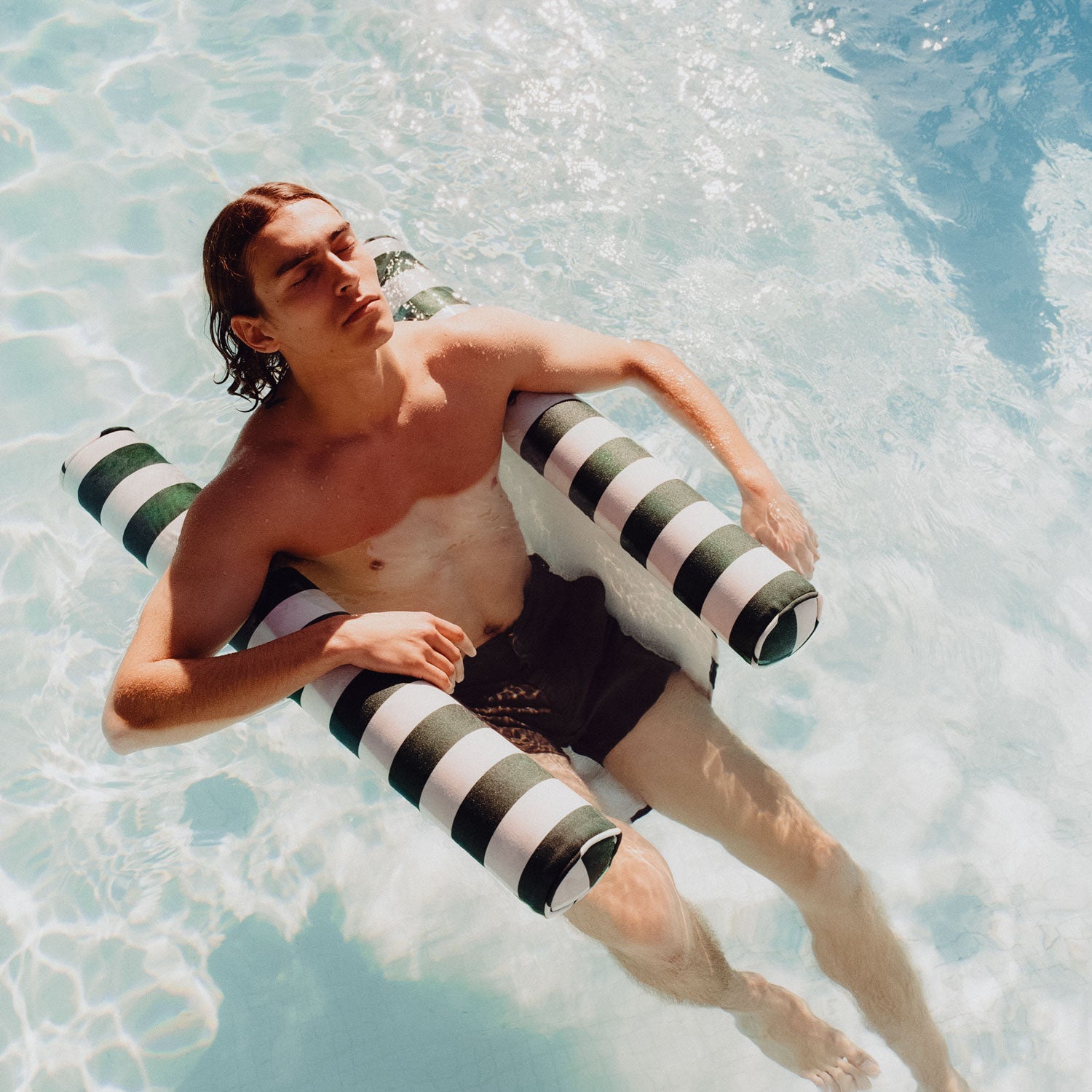 A man sitting on a pool toy for adults in a swimming pool.